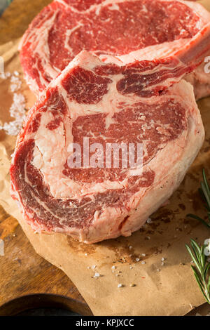 Raw Red Grass Fed Tomahawk Steaks with Rosemary Stock Photo
