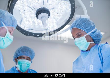 Doctors performing operation in hospital theatre. Stock Photo