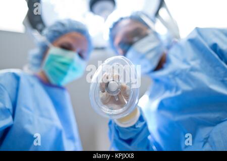 Nurse holding gas mask, female doctor in the background. Stock Photo
