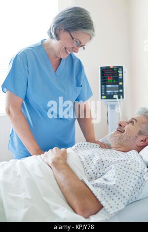 Female nurse talking to male patient in hospital bed. Stock Photo
