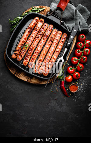 Grilled sausages bratwurst in grill frying-pan on black background. Top view. Traditional German cuisine. Stock image Stock Photo