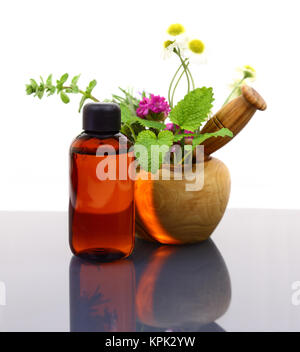 Mortar and pestle with fresh herbs and essential oil bottle Stock Photo