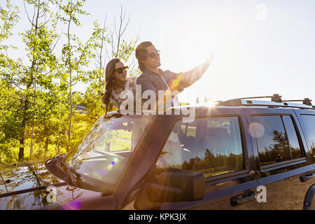 Young couple taking selfies with a cell phone in their vehicle; Edmonton, Alberta, Canada Stock Photo