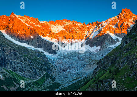 Sunrise glow on the peaks above l'A Neuve Glacier, viewed from La Fouly, Swiss Val Ferret, Alps; La Fouly, Val Ferret, Switzerland Stock Photo