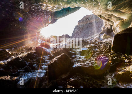 The sun shines into a cave beneath the ice of Root Glacier in Wrangell-St. Elias National Park; Alaska, United States of America Stock Photo