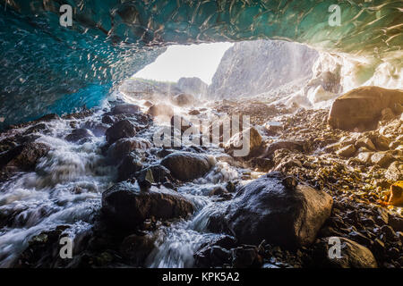 Water cascades over rocks inside a cave beneath the ice of Root Glacier in Wrangell-St. Elias National Park; Alaska, United States of America Stock Photo