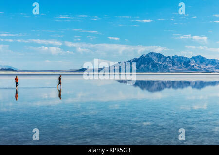Tourists walk in inches deep salt water near Bonneville Salt Flats; Wendover, Utah, United States of America Stock Photo
