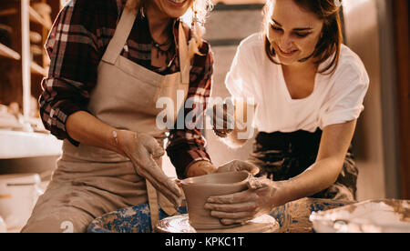Woman potter teaching the art of pot making. Women working on potters wheel making clay objects. Stock Photo