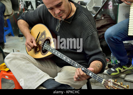 Musician playing a traditional bouzouki in a group of buskers along pavement in central Athens, Greece Stock Photo