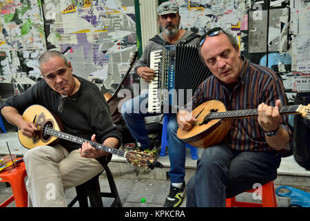 Group of three musician buskers playing traditional instruments along pavement in central Athens, Greece Stock Photo