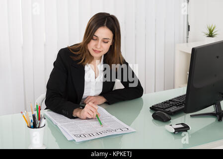 Businesswoman Reading Classifieds On Newspaper Stock Photo