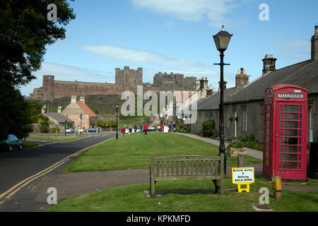 Bamburgh village and castle, Northumberland, England. View down Front Street with traditional red K6 telephone box. Stock Photo