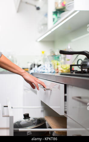 Pretty, young woman in her modern and well equiped kitchen putting cups into the dishwasher Stock Photo