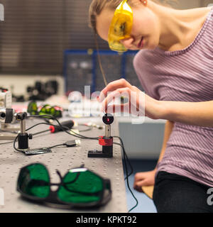 Female scientist carrying out research experiments in a quantum optics lab (color toned image)
