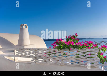 Purple Bougainvillea in front of volcanic caldera in Oia village on Santorini island, Greece Stock Photo