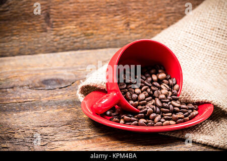 Red coffeecup and plate with spilled coffeebeans Stock Photo