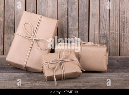 Three packages wrapped in brown paper and string on old wood deck Stock Photo