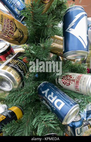 Small green artificial Christmas tree decorated with empty blue, gold, blue and white beer and cider cans at Meredith Music Festival. Stock Photo