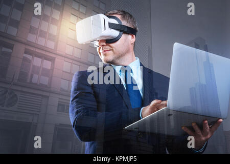 Smiling entrepreneur wearing VR headset using laptop Stock Photo