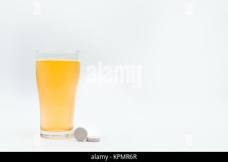 Two effervescent tables on white background and orange effervescent bubbles of calcium and vitamin C effervescent tablets in transparent glass. Vitami Stock Photo