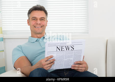 Man Reading Newspaper Sitting On Sofa Stock Photo