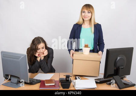 An employee in the office happily keeps things close sad colleague Stock Photo