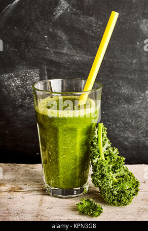 Healthy vegetable smoothie with fresh cole or kale and yoghurt blend with a fresh green leaf propped up against the glass, rustic background Stock Photo