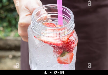 Hand on serving glass of iced strawberry soda drink Stock Photo