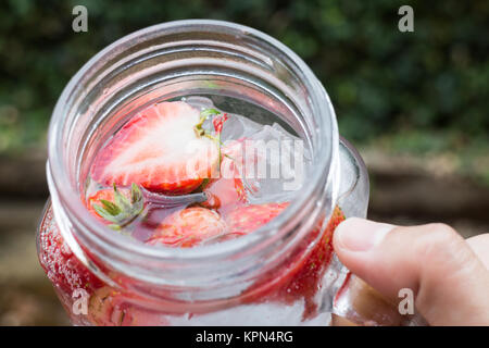 Hand hold glass of iced strawberry soda drink Stock Photo