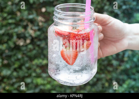 Hand hold glass of iced strawberry soda drink Stock Photo