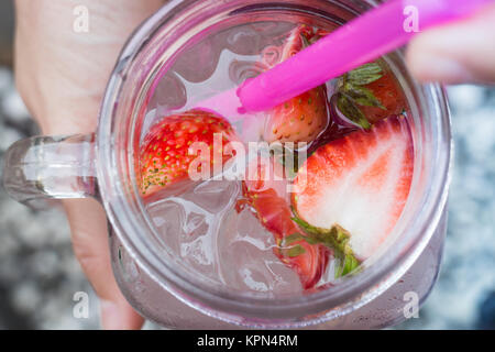 Hand hold glass of iced strawberry soda drink Stock Photo