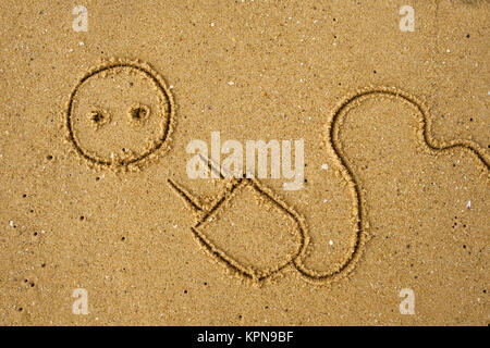 Electric plug drawn on sand. Stock Photo