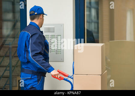 Delivery Man With Trolley Using Security To Enter Building Stock Photo