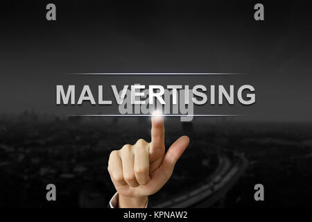 business hand pushing malvertising button on black blurred background Stock Photo