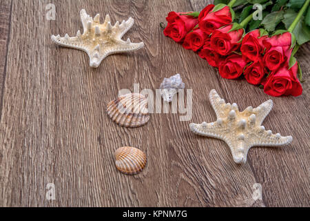 Starfishes, shells and red roses on a wooden background Stock Photo