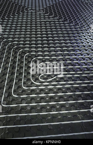Radiant underfloor heating installation with flexible tubing mounted on insulation boards Stock Photo