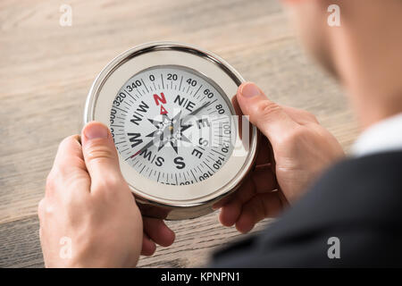 Close-up Of Businessman Holding Compass In Office