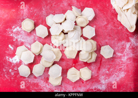 raw homemade dumplings with minced pork on the red surface. Stock Photo
