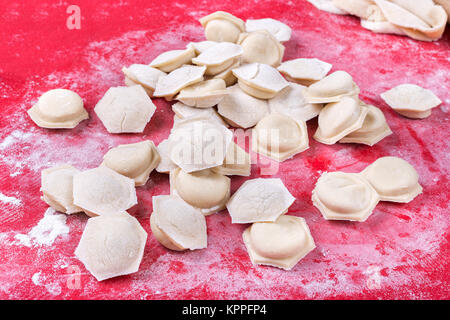 raw homemade dumplings with minced pork on the red surface. Stock Photo