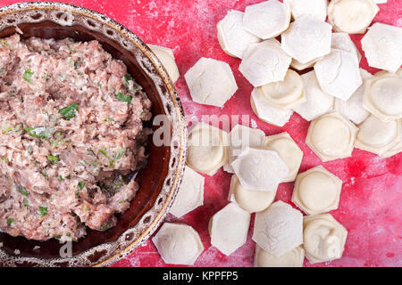 raw homemade dumplings with minced pork on the red surface. Stock Photo
