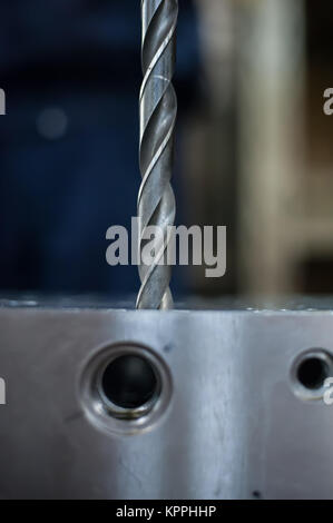 Large and powerful automatic heavy industrial drill bit cutting the metal block at the factory Stock Photo