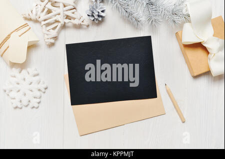 Mockup Christmas black greeting card letter in envelope with white tree, flatlay on a white wooden background, with place for your text, Flat lay, top view photo mock up Stock Photo