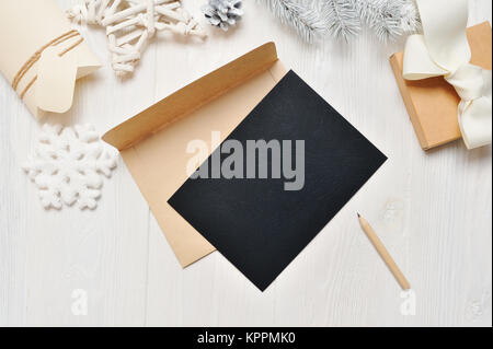Mockup Christmas black greeting card letter in envelope and pencil, flatlay on a white wooden background, with place for your text, Flat lay, top view photo mock up Stock Photo