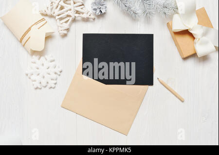 Mockup Christmas black greeting card letter in envelope and pencil, flatlay on a white wooden background, with place for your text, Flat lay, top view photo mock up Stock Photo