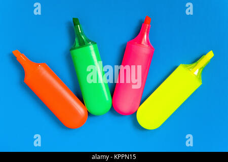 Multicolored markers lie on a blue sheet of paper. Stationery. Stock Photo
