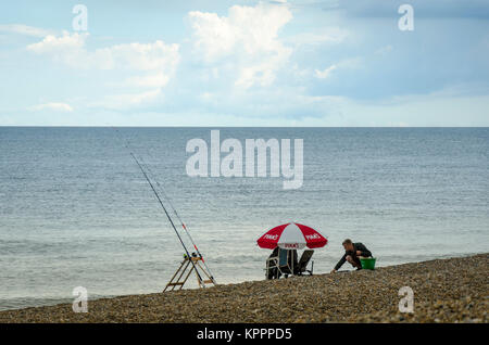 People sat fishing on the beach. Aldeburgh English coastal town in Suffolk, UK Stock Photo