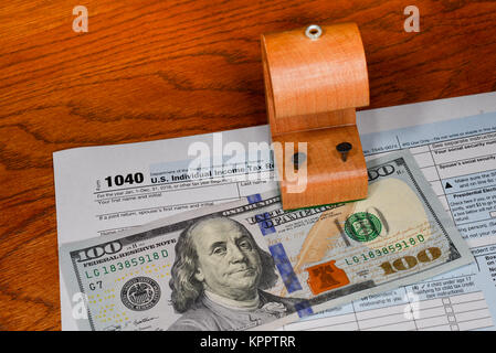 A US individual income tax form with a $100 bill and a wooden tax (tack) shelter concept tax savings. Stock Photo