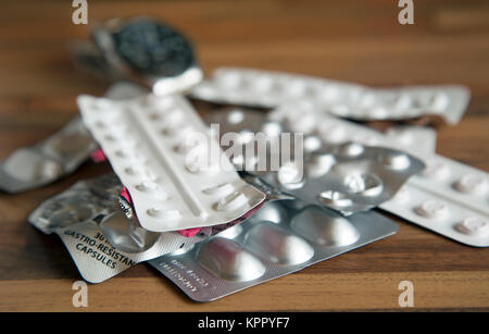 A pile of part used prescription drugs on a tabletop with a watch in the background shot in landscape format. Stock Photo