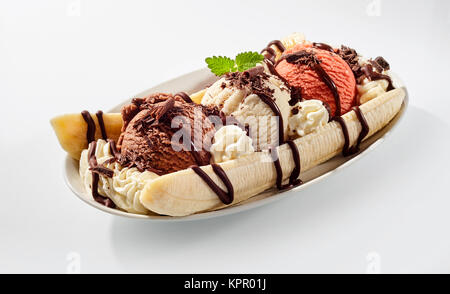 Delicious sweet banana split ice cream dessert with garnishment of chocolate syrup, and peppermint leaf on top in bowl on table Stock Photo