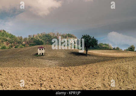 Little funny house in the middle of a plowed field. Loiano, Bologna, Italy. Stock Photo